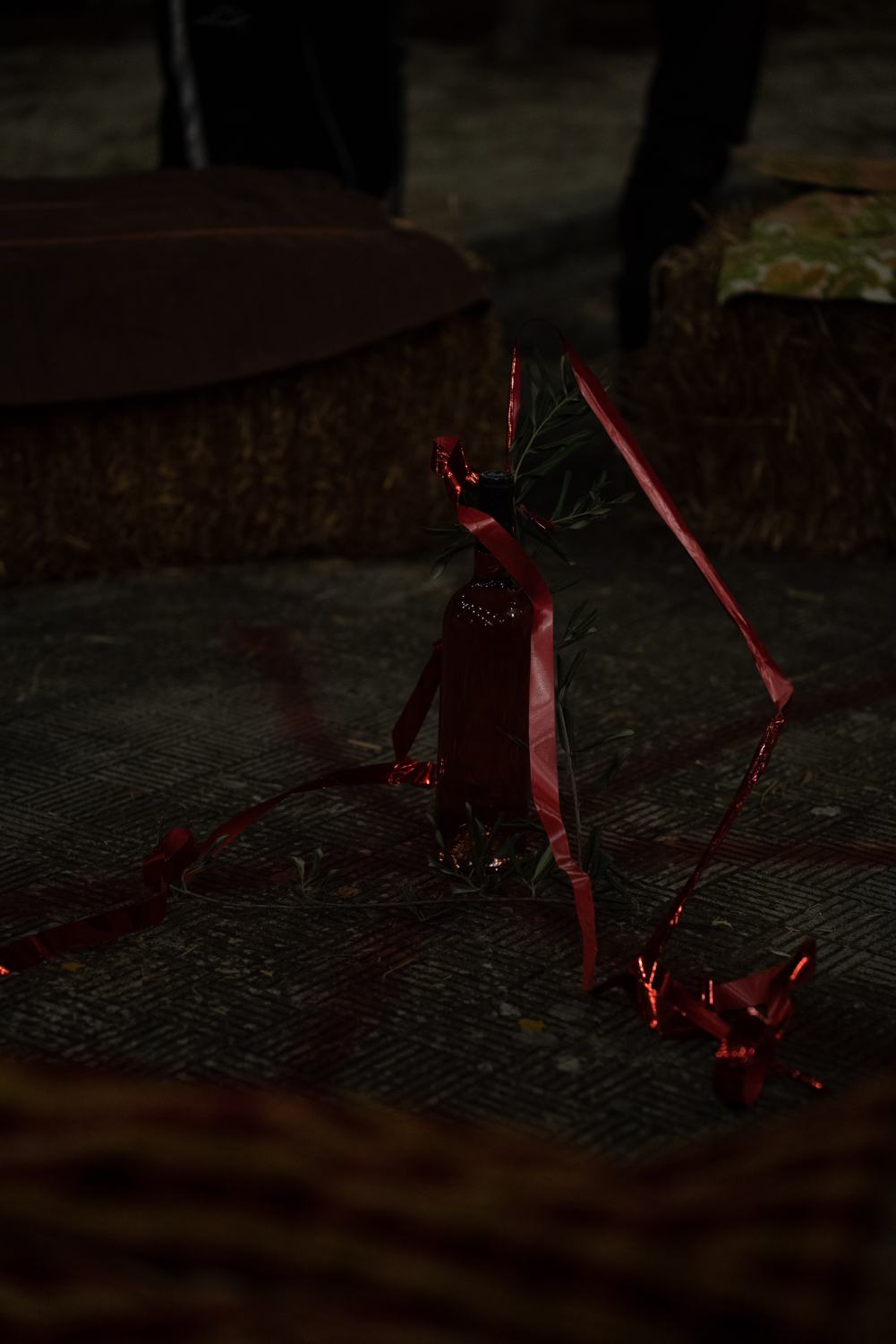 A bottle left on the ground, tied with red ribbon and an olive branch A bottle left on the ground, tied with red ribbon and an olive branch